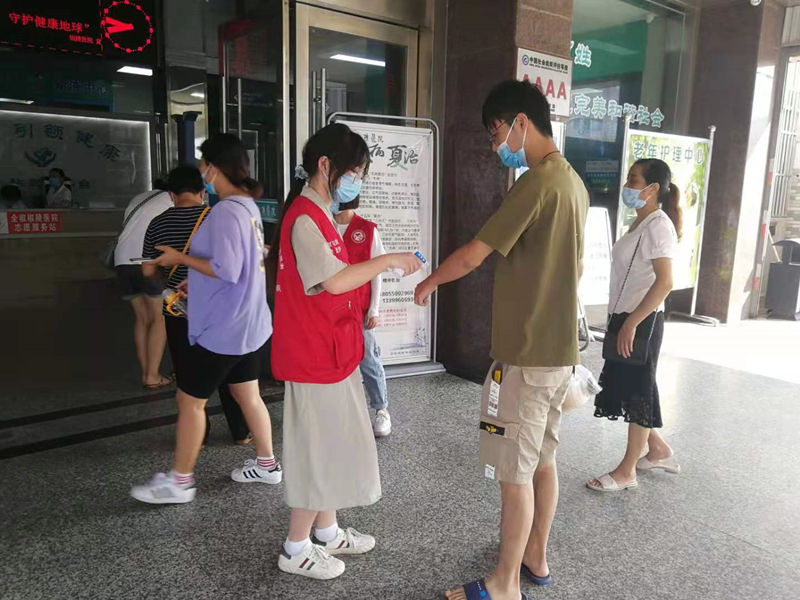 01图为志愿者在椒陵医院大门前测量就诊患者体温，提醒过往群众扫安康码、佩戴口罩。皖南医学院姚忻提供
