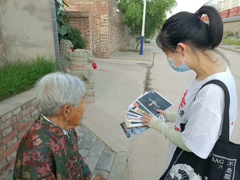 06+团队成员向村民展示团队设计制作的明信片，讲解明信片中蕴含的文化与知识+浙江大学谢尹提供
